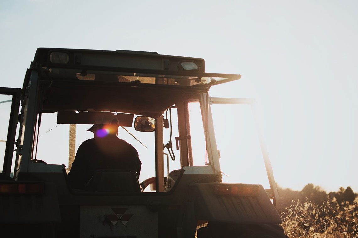 "silhouette of man riding tractor"